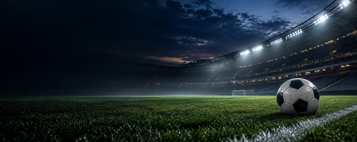 Football on a floodlit stadium pitch at dusk